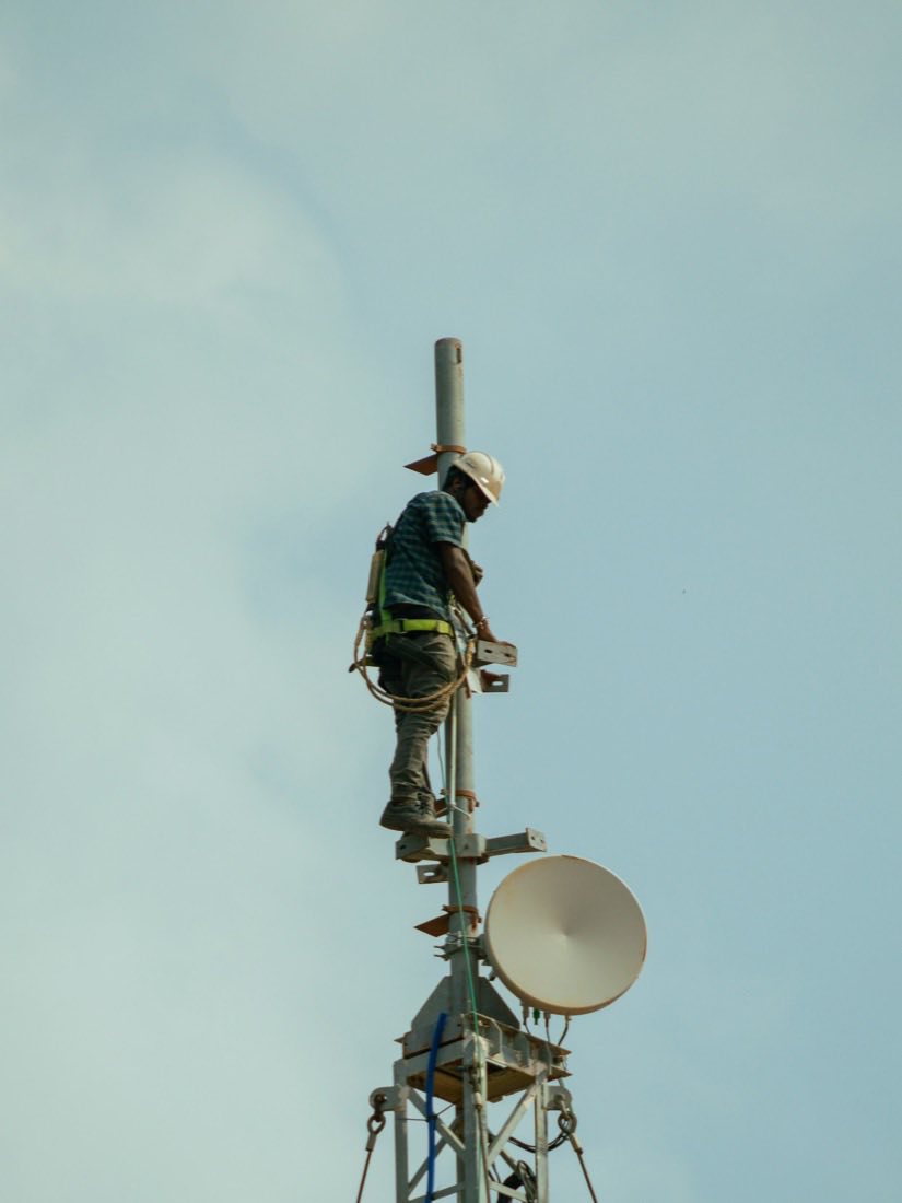 Technik instaluje bezdrátovou anténu na vrcholu telekomunikačního stožáru